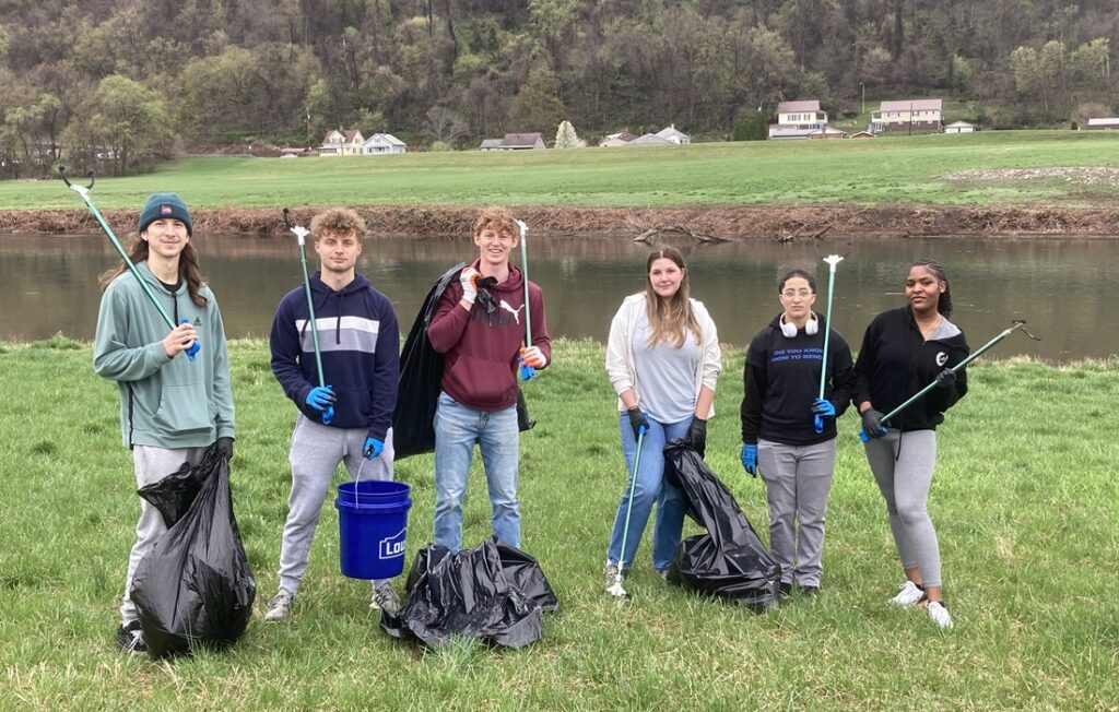 students pose next to river bank during cleanup