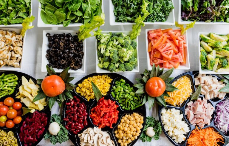 Assortment of colorful fruits, vegetables, meats and cheeses on table