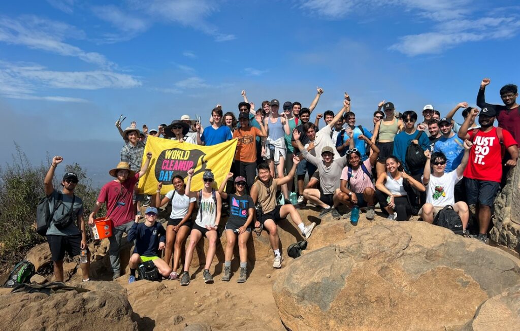 diverse group of people pose on rock with sign