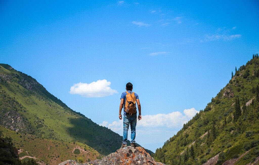 man standing on peak next to mountains